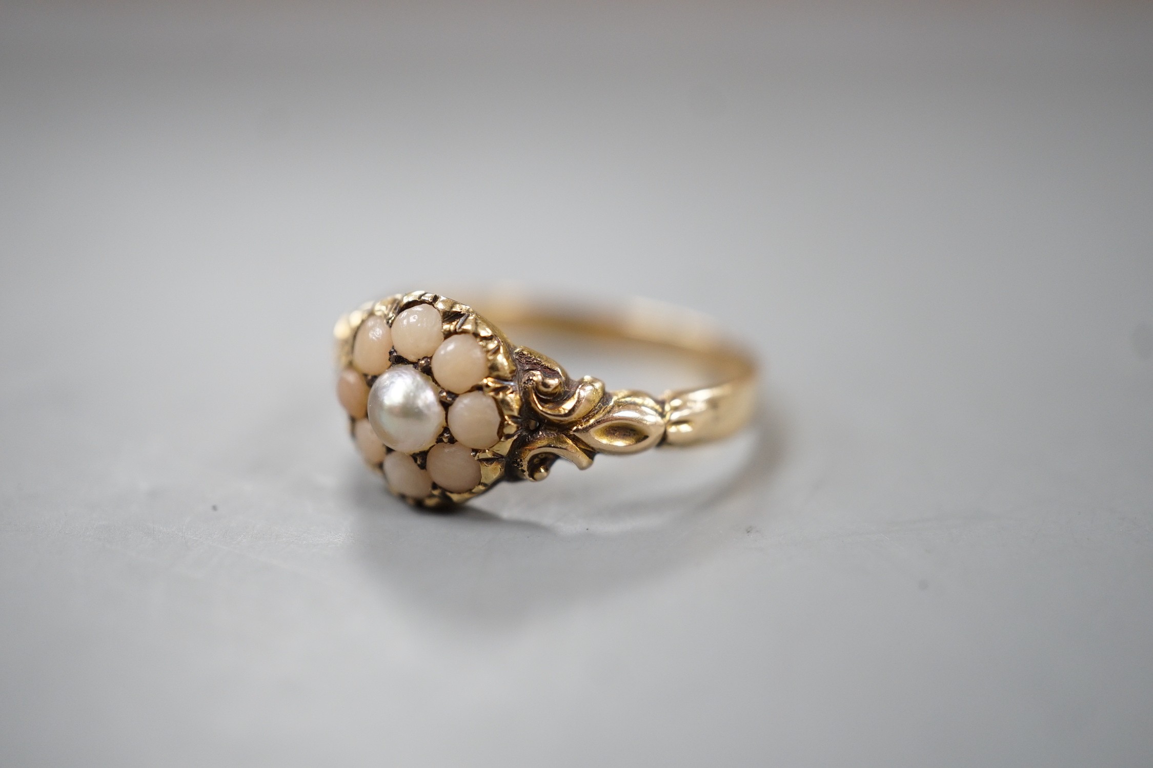 An early 20th century yellow metal, split coral and split pearl cluster set ring, size P, gross weight 2.5 grams.